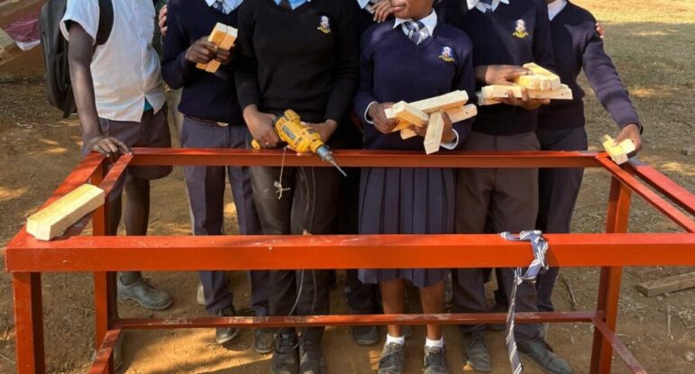 The learners pose for a picture with the two teachers after successfully completing a lesson.